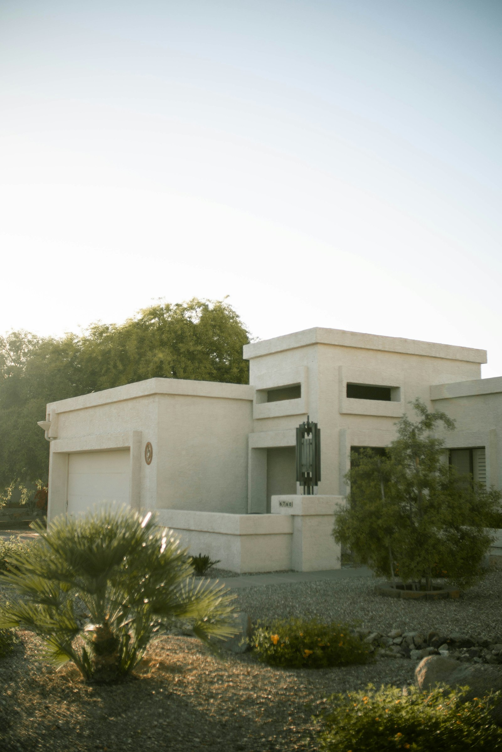 Cream stucco single family desert home with palms and gravel yard, typical Chandler housing