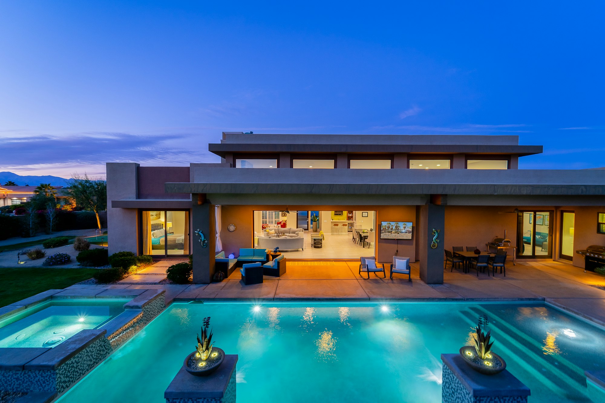 Upscale Phoenix area desert home with a pool lit at dusk beneath the mountains